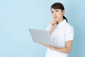 パソコンを見ながら悩む看護師