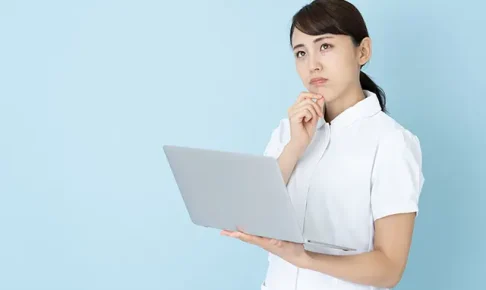 パソコンを見ながら悩む看護師