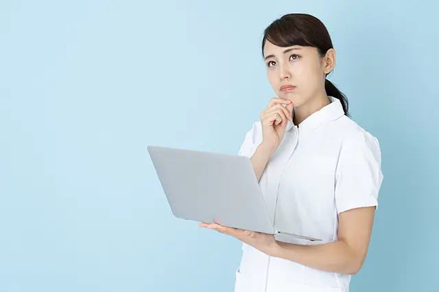 パソコンを見ながら悩む看護師