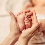 赤ちゃんの足を持つ母の手