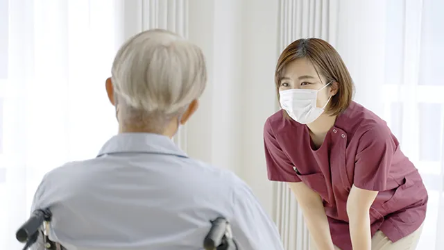 車椅子の老人に話しかける看護師